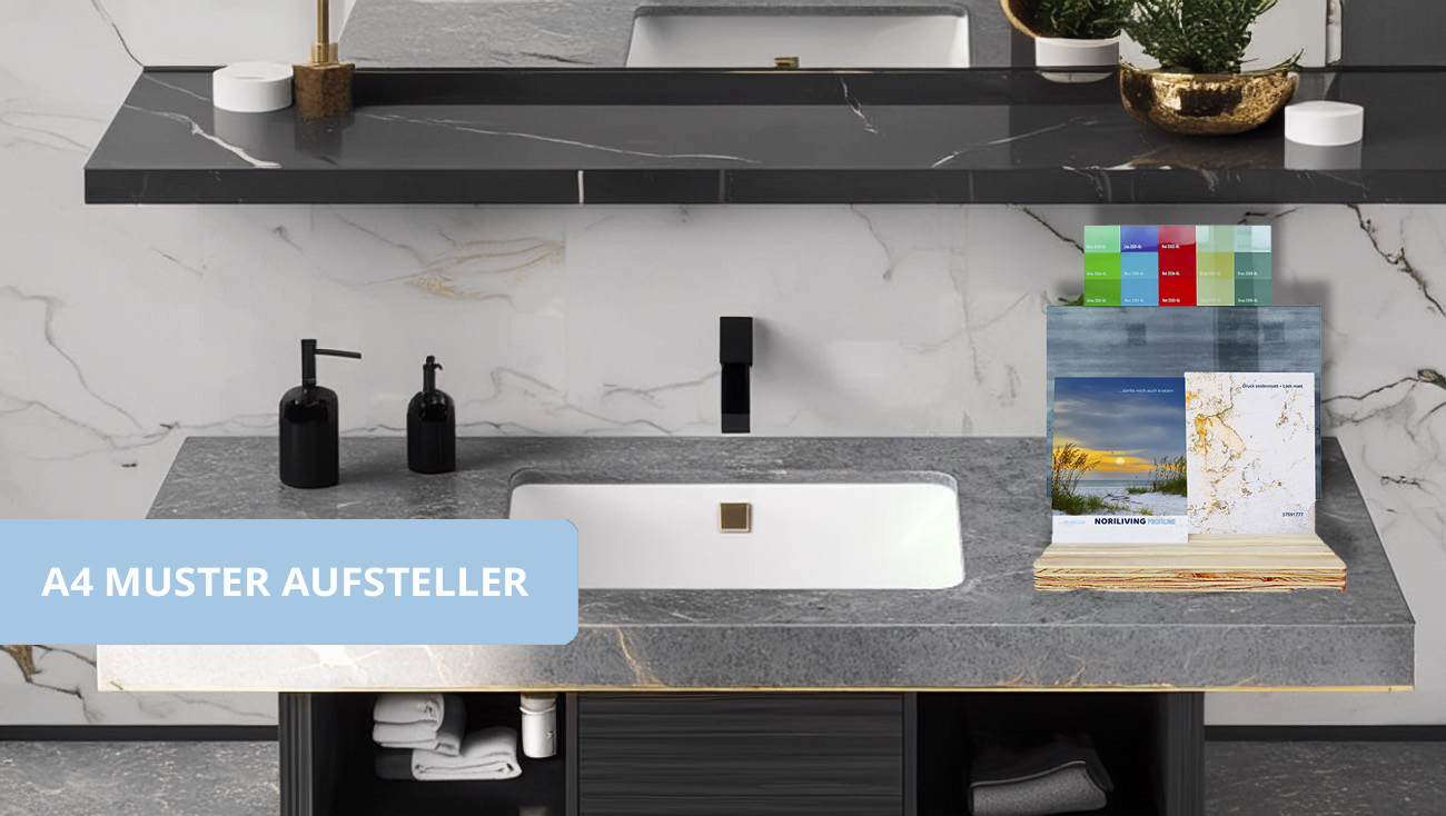 Badezimmer mit grauem Waschbecken, schwarzem Wasserhahn, und A4 Musteraufsteller auf der Ablage. Elegantes Marmordesign an der Wand.